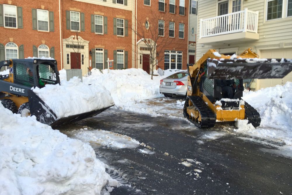 The Absolute Tree snow removal team clearing out a parking lot with skid steers in McLean, VA.